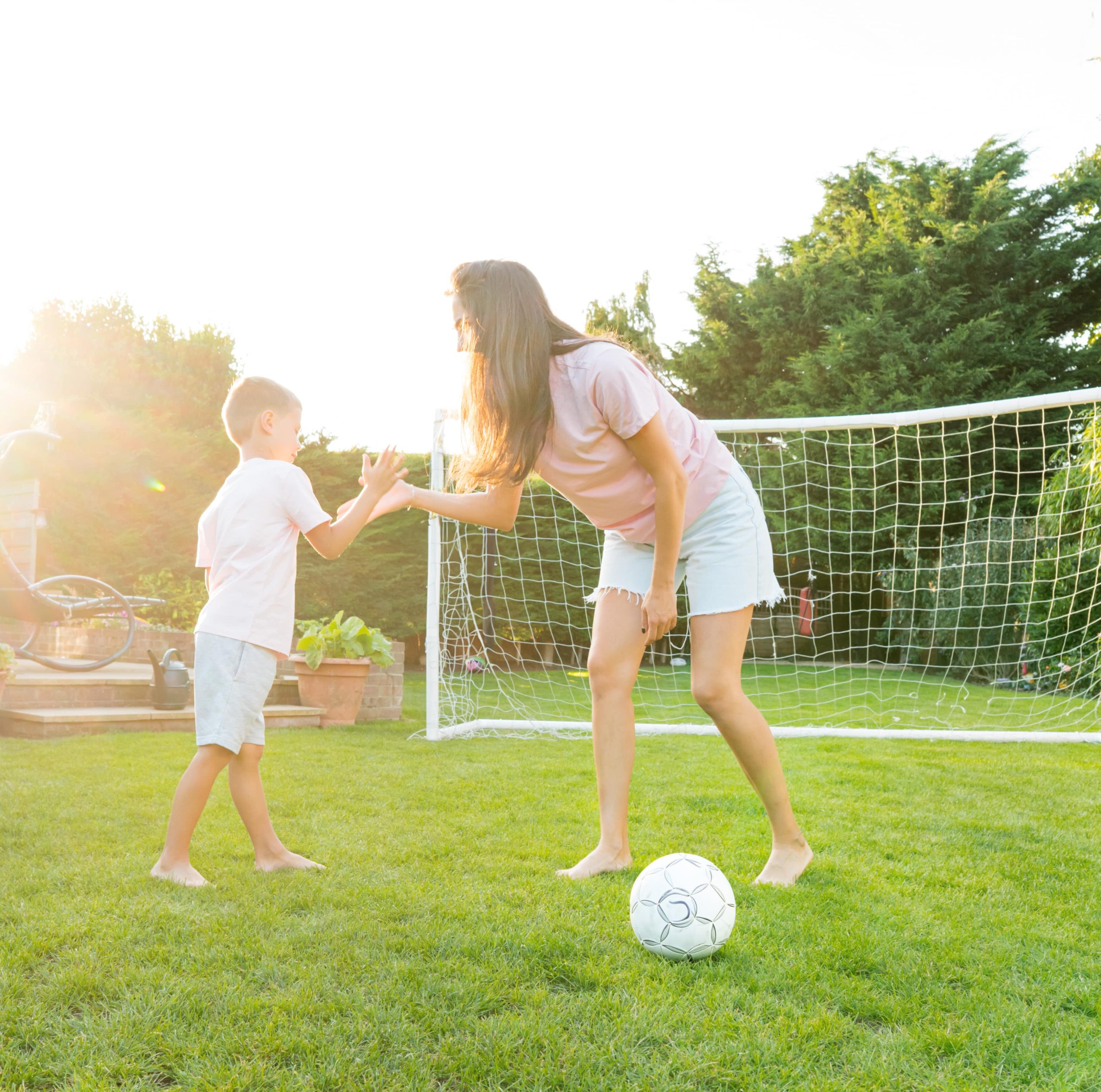 mom and kid playing soccer outside